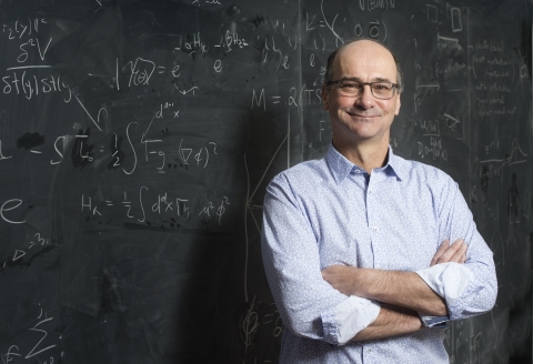 Portrait of a man standing in front of a blackboard of equations